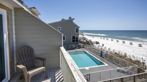 Une terrasse avec une piscine donnant sur une plage parsemée de parasols.