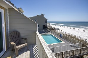 A deck with a pool overlooking a beach with umbrellas. - Gulf Front Townhouse w/ Community Pool, Dune Allen Beach (Sant Rosa Beach)