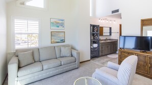Un salon avec un canapé, des fauteuils, une table basse et un téléviseur.
