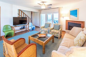 A living room with a television, wicker furniture, a sofa, and a fireplace.