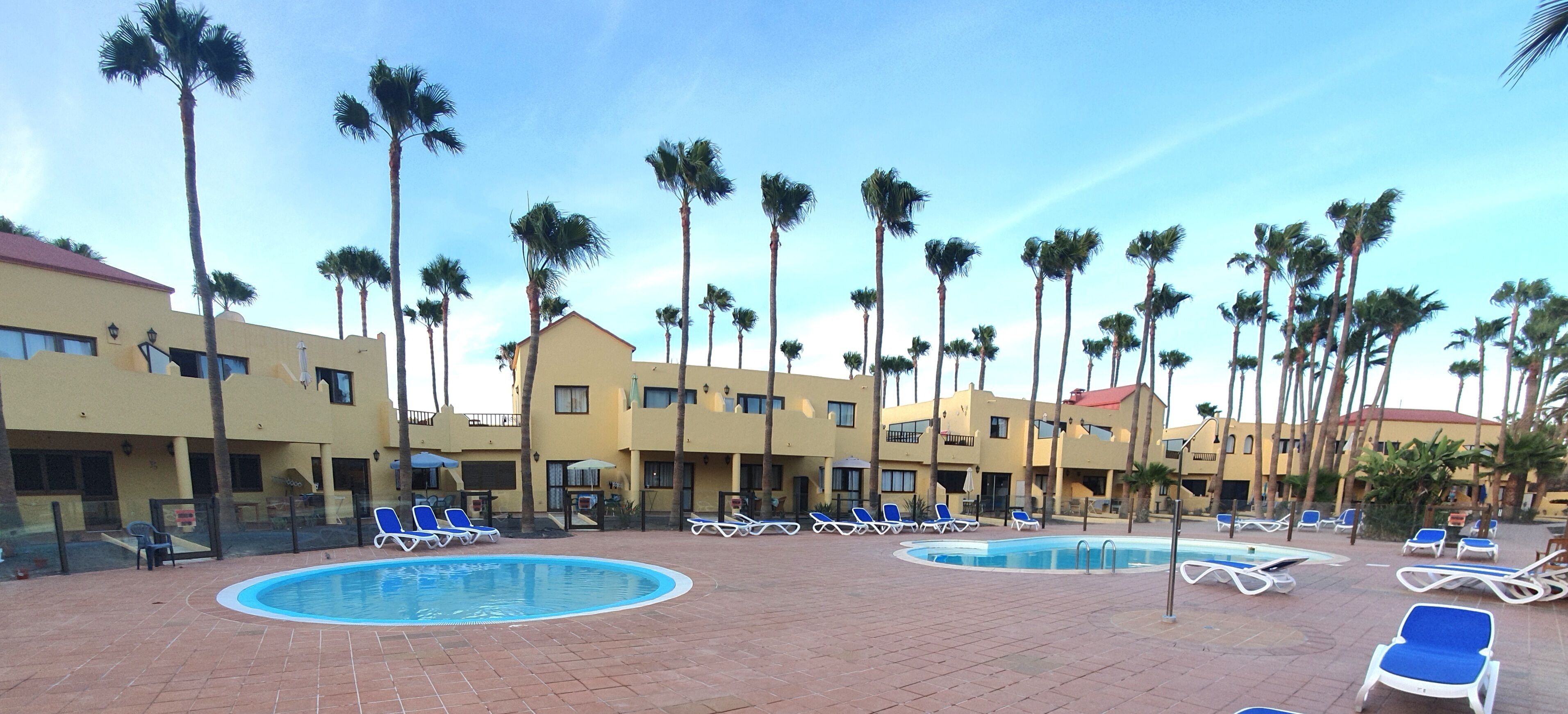 A resort with a pool area, palm trees, and multiple buildings with balconies.