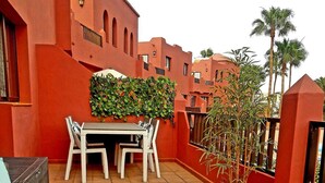 A patio with a table and chairs, a potted plant, and a wicker sofa. - Oasis Royal - Beautiful Corralejo Apartment (Corralejo)