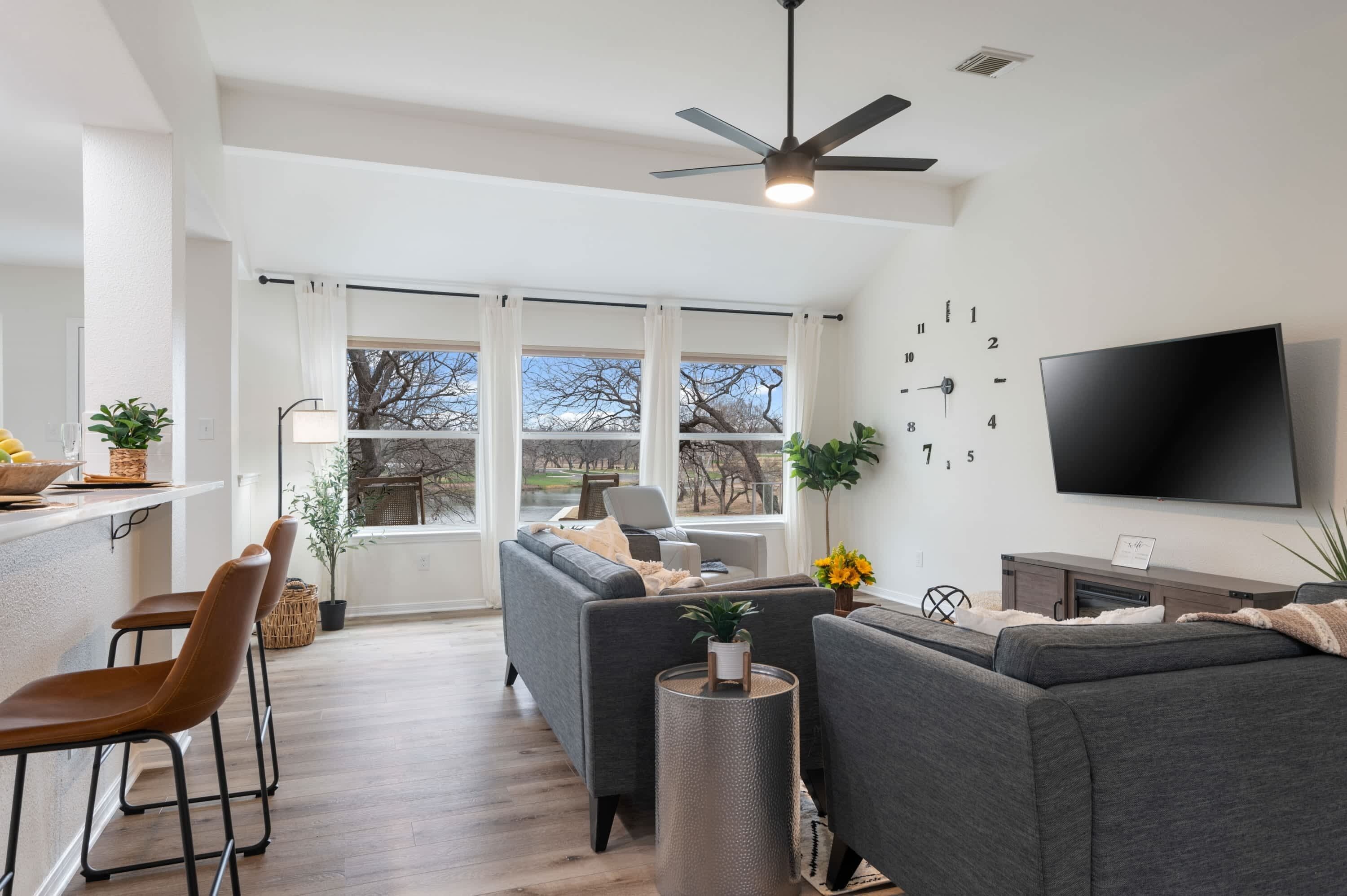 A modern living room with a sofa, TV, and dining area with chairs and a table.
