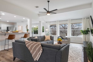 A modern living area with a sofa, chairs, a dining area, and a kitchen.
