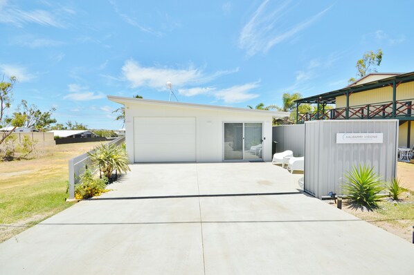 A modern building with a garage, a covered outdoor seating area, and a sign for "KALBARRI VISIONS."