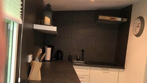 A modern kitchen with dark tiles, white cabinets, and a wooden countertop. - Haus Onel 1 (Schmallenberg)