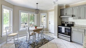 A kitchen with white cabinets, a black stove, and a patterned rug. - Circa 1870, Historic | Central | Original (Savannah)