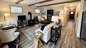 A cozy living room with a fireplace, white sofas, a television, and a bookshelf.