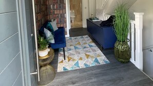 A hallway with a blue sofa, a patterned rug, a bookshelf, and a staircase. - Detached Luxury House in the Hart of Islington (London)
