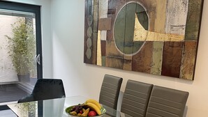 A modern dining area with a glass table, leather chairs, and a fruit bowl. - Detached Luxury House in the Hart of Islington (London)