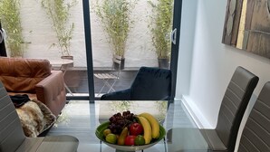 A modern living room with a glass coffee table, leather sofas, and a view of a balcony with potted plants. - Detached Luxury House in the Hart of Islington (London)
