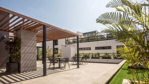Een buitenpatio met een pergola, zitplaatsen en potplanten.