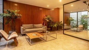 Een moderne woonkamer met een bank, twee fauteuils, een salontafel en grote ramen.