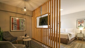 Een moderne hotelkamer met een bed, een bureau, een stoel, een klein tafeltje en een decoratief scherm.