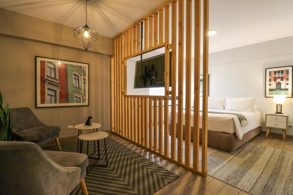 Une chambre d’hôtel moderne équipée d’un lit, d’un bureau, d’une chaise, d’une petite table et d’un paravent décoratif.