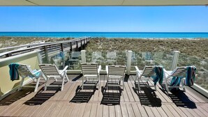 A deck with white chairs and a glass railing overlooking a beach. - Poseidon's Rest | Gulf Front Home | Gorgeous Gulf Views | Dune Walkover (Navarre Beach)