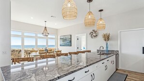 A modern kitchen with a large island, white cabinetry, and a view of the beach. - Poseidon's Rest | Gulf Front Home | Gorgeous Gulf Views | Dune Walkover (Navarre Beach)