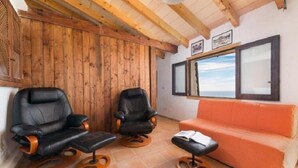 A room with two black leather chairs, an orange sofa, and a wooden ceiling. - Shelter "Es Mirador" Cami de S'Illeta - Port de Soller (Puerto de Sóller)