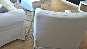 Un salon avec un mur en pierre, une cheminée, un téléviseur à écran plat, un canapé blanc et un fauteuil.