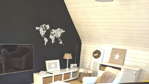 Un salon moderne avec un canapé blanc, une table basse, un téléviseur et une décoration murale représentant une carte du monde.