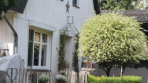 Une maison blanche avec une fenêtre en forme d’étoile, une clôture en bois et une pelouse bien entretenue.