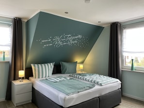 Een moderne slaapkamer met een bed, nachtkastjes en een muur met een ontwerp van een sterrenhemel.