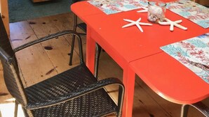 A dining area with a red table, starfish decoration, and a wicker chair.