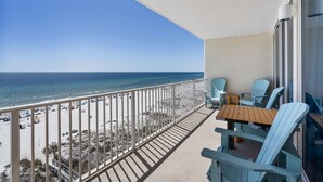 Un balcon avec vue sur la plage et l’océan. On y trouve deux chaises et une table.