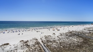 A beach with tents and umbrellas, a sandy shore, and a clear blue sky. - Lighthouse 502 by Liquid Life (Gulf Shores)