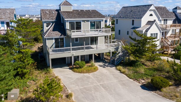 A two-story house with a balcony and a covered porch. - Serenity Now: Dog-Friendly Home in Golf Course Community w/ Water Views (Nags Head)