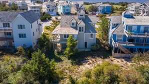 A coastal residential area with houses featuring gabled roofs and multiple stories. - Serenity Now: Dog-Friendly Home in Golf Course Community w/ Water Views (Nags Head)