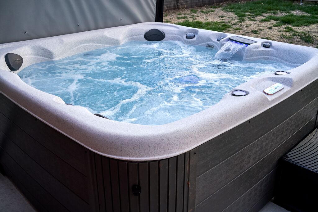 A hot tub with a control panel and multiple jets, surrounded by a wooden deck.
