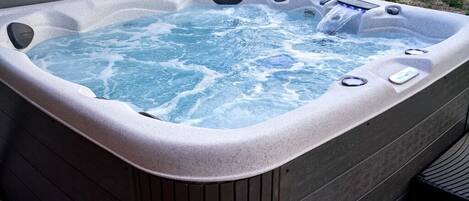 A hot tub with a control panel and multiple jets, surrounded by a wooden deck.