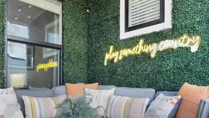 A cozy seating area with a grey sofa, a metal table, and a green wall with a neon sign.