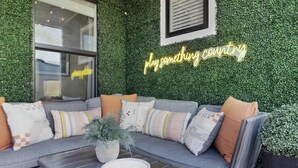 A cozy outdoor seating area with a gray sofa, multiple cushions, and a potted plant.