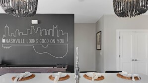 A modern kitchen with a city skyline mural, a stainless steel sink, and woven placemats on the counter.