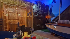 A dining table with a candle, wine glasses, and a fruit platter. - Shipwrecked-VERY COOL couple's ATL area theme suite! (Carroll County)