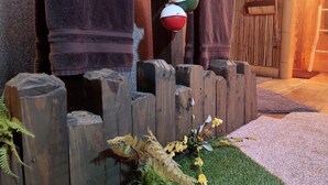 A wooden fence with a small garden area, including a fern and a flower arrangement. - Shipwrecked-VERY COOL couple's ATL area theme suite! (Carroll County)