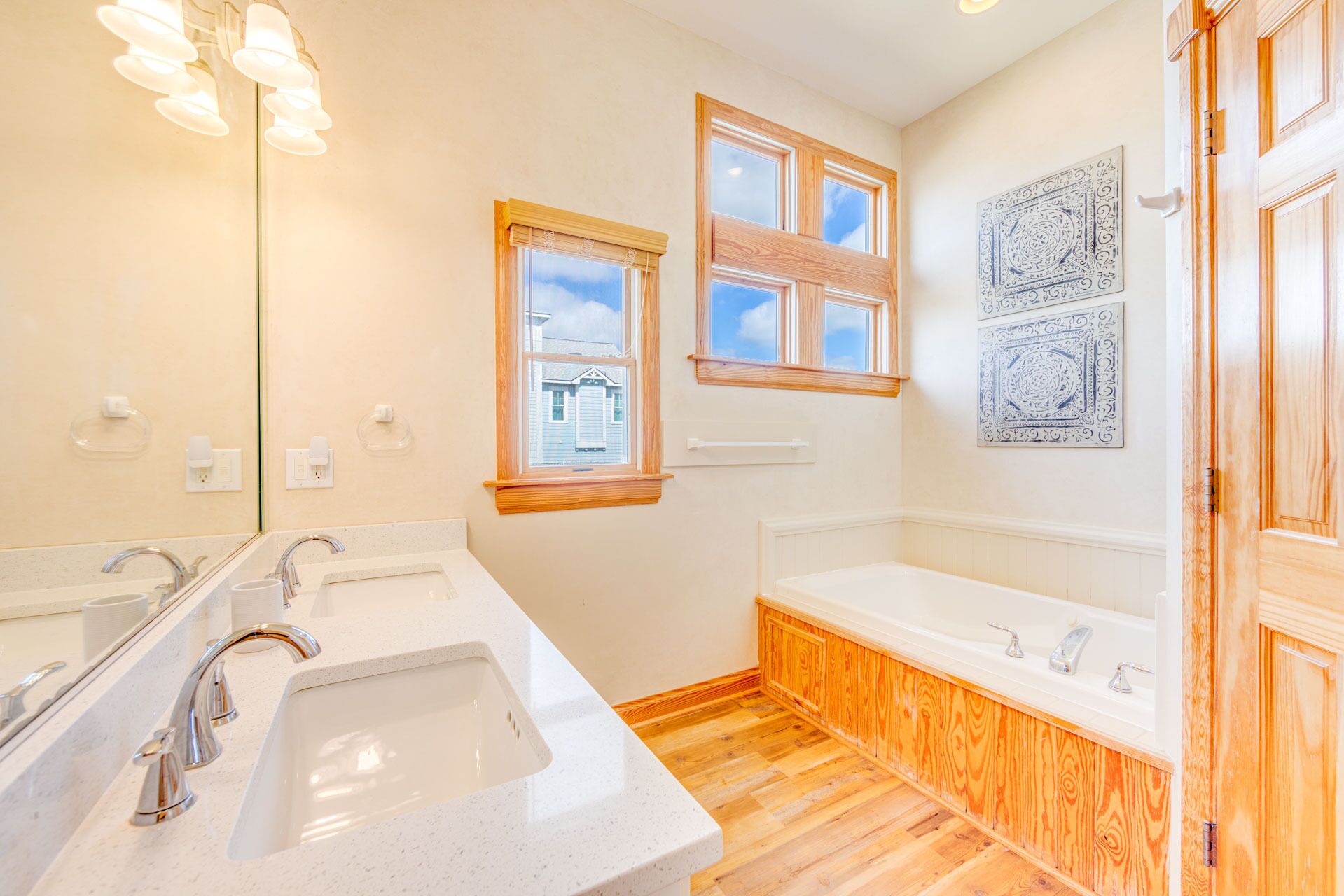 A bathroom with two sinks, a bathtub, and wooden flooring.