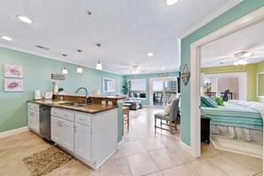 Cozy living space with a kitchen, dining area, and guest room featuring a large bed.
