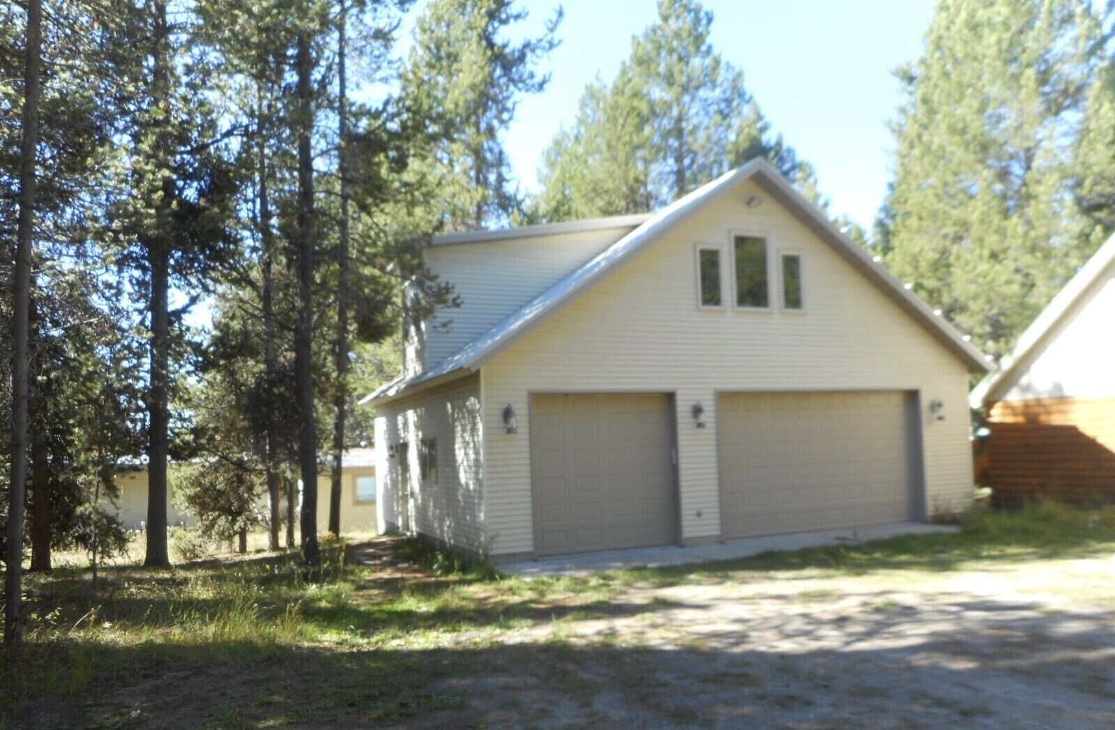 Einbungalow mit Garage, umgeben von Bäumen.