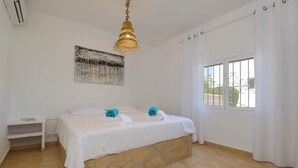 A bedroom with a bed, a nightstand, a painting, a window with curtains, and a hanging light fixture. - Villa La Perla CALPE : Great Seaview & Large Pool (Calpe)