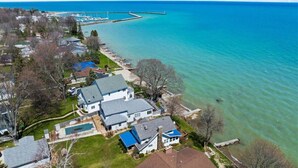 An aerial view of a residential area with houses, a swimming pool, and a marina with boats. - Krusty Krab! Lakefront Getaway, Walk to Downtown! (Port Sanilac)