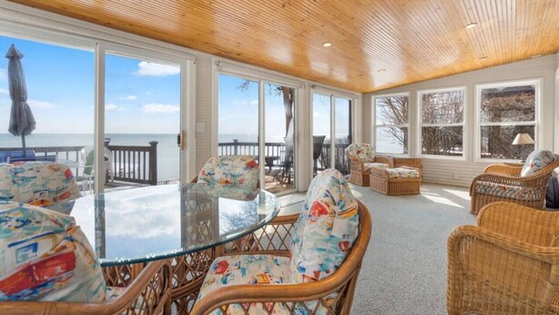 A sunroom with a wooden ceiling, large windows, wicker furniture, and a glass table. - Krusty Krab! Lakefront Getaway, Walk to Downtown! (Port Sanilac)