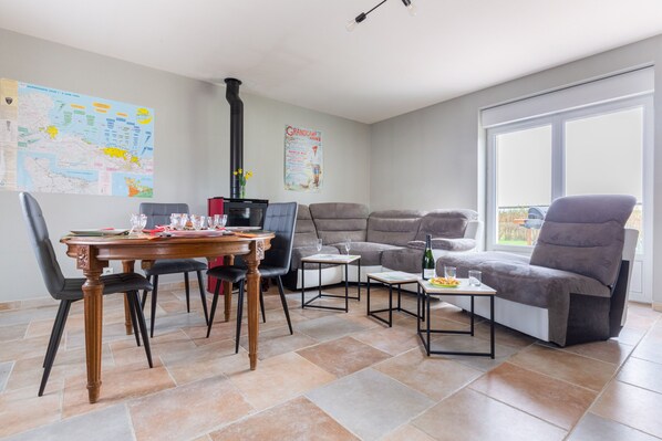 A modern living room with a dining table, two sofas, and a fireplace.