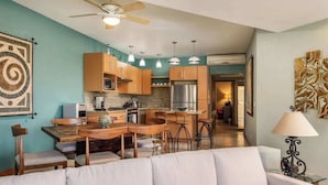 A modern kitchen with wooden cabinets, a central island, pendant lights, and a ceiling fan.