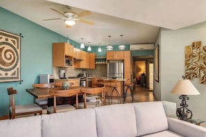 A modern kitchen with wooden cabinets, a central island, pendant lights, and a ceiling fan.