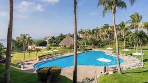 A resort pool with lounge chairs and palm trees.