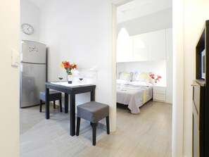 A compact kitchen with a refrigerator, a dining table with chairs, and a small bench. - Black and White Movie Apartment, 2 People, 3 Floor, 35 square meters (Roma)