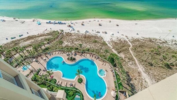 Un resort con una grande piscina, accesso alla spiaggia e vista sull'oceano.